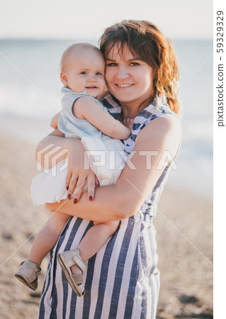 Happy mother and baby daughter posing near sea. 59329329