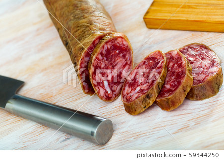 Thin salchichon sausage slices on wooden background, view from above Thin salchichon sausage slices on wooden background, view from above 59344250