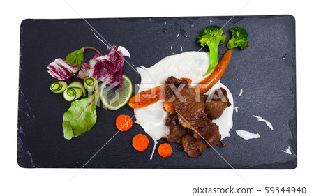 Tasty chicken heart with cream sauce served with vegetables at plate 59344940