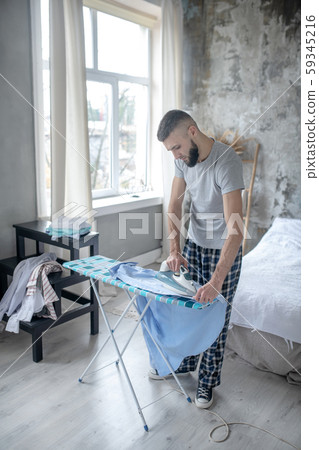Top view of man wearing pajamas ironing clothing 59345216