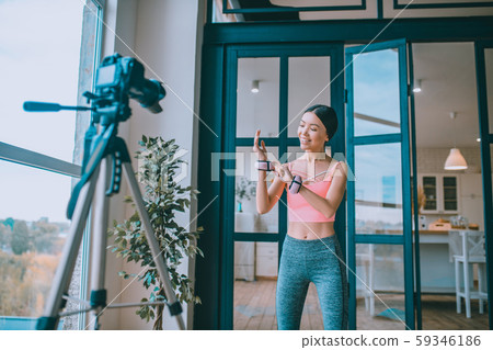 Dark-haired fitness trainer showing her arm wrist weights Dark-haired fitness trainer showing her arm wrist weights 59346186