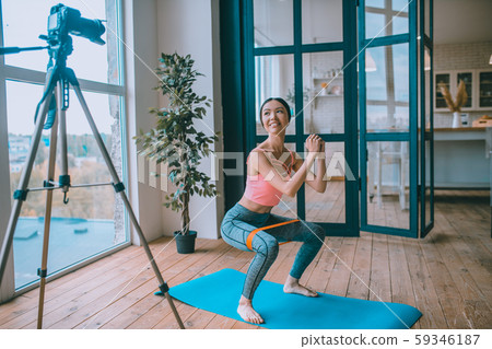 Fitness trainer doing sit ups with resistance band in front of camera Fitness trainer doing sit ups with resistance band in front of camera 59346187