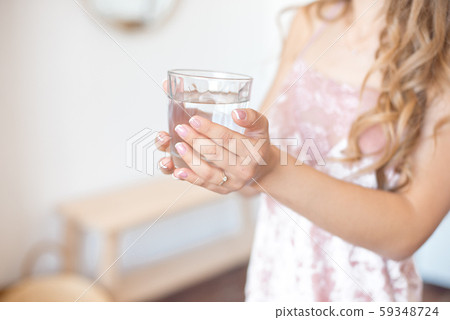 Female hands holding a clear glass of water. Slime body on background. Healthy lifestyle. 59348724