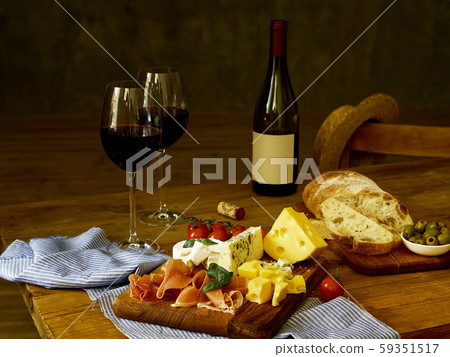 A bottle of wine and two glasses sand snacks  59351517