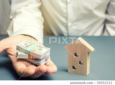 Businessman holds dollars in hands near wooden house. Real estate investment concept. Mortgage. Loan for housing. Credit. Rent. Rental. Buying a property. The accumulation of money. Selling a house 59352211