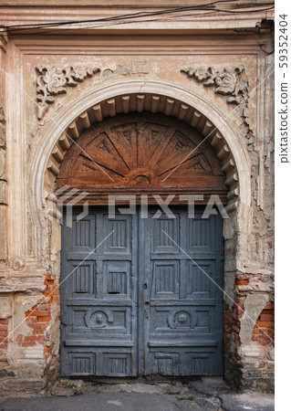 Old arched wooden door in ornate wall 59352404