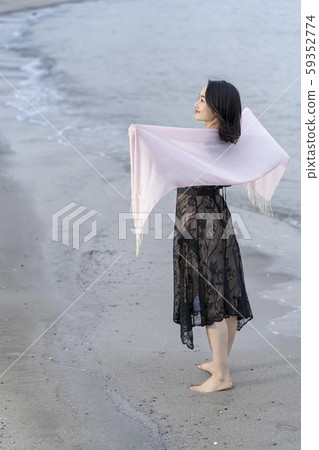 A young woman's lifestyle traveling alone elegantly walking barefoot on the beach A young woman's lifestyle traveling alone elegantly walking barefoot on the beach 59352774