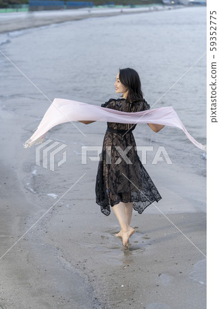 A young woman's lifestyle traveling alone elegantly walking barefoot on the beach A young woman's lifestyle traveling alone elegantly walking barefoot on the beach 59352775