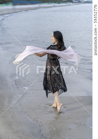 A young woman's lifestyle traveling alone elegantly walking barefoot on the beach A young woman's lifestyle traveling alone elegantly walking barefoot on the beach 59352776