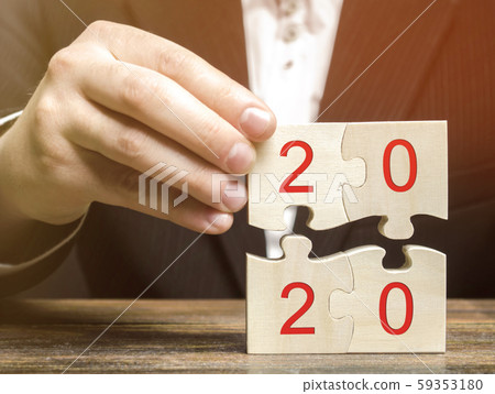 Businessman collects wooden puzzles with the inscription 2020. New Year concept. Plan, planning. Business goals and strategy for the future. Businessman collects wooden puzzles with the inscription 2020. New Year concept. Plan, planning. Business goals and strategy for the future. 59353180