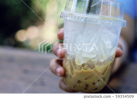 Close-up hand woman holding iced cappuccino coffee and ice is melting. Close-up hand woman holding iced cappuccino coffee and ice is melting. 59354509