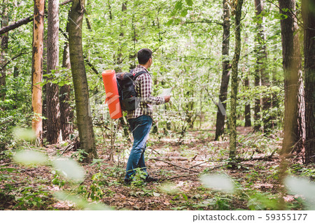 Man with Backpack and map searching directions in wilderness area. Tourist with backpack using map Man with Backpack and map searching directions in wilderness area. Tourist with backpack using map 59355177