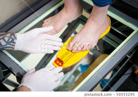 Orthopedics and medicine. Young Caucasian doctor hands man tattoo latex gloves size measurement 59355295