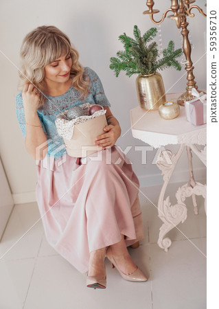 Young beautiful blonde woman holding a box of new year toys Young beautiful blonde woman holding a box of new year toys 59356710