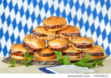 Traditional oven fresh Bavarian meat loaf on crisp rolls, the Bavarian flag in the background Traditional oven fresh Bavarian meat loaf on crisp rolls, the Bavarian flag in the background 59358013