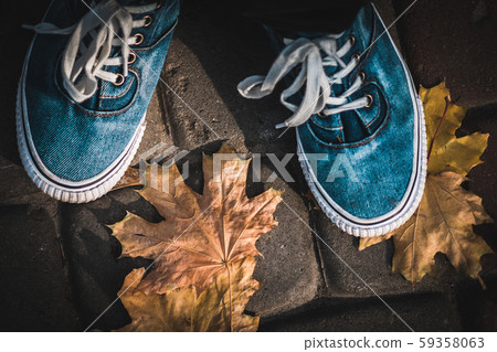 Blue sneakers on a background of yellow autumn leaves. 59358063