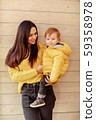 Young mother and baby stand on wooden wall 59358978