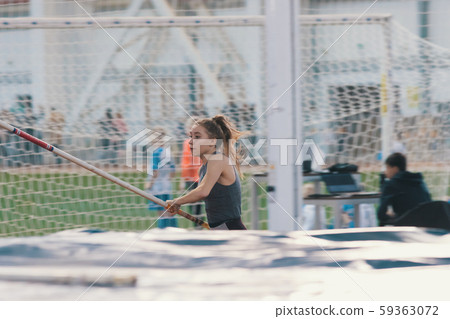 Pole vaulting indoors - young sportive woman with ponytail running with a pole in her hands 59363072