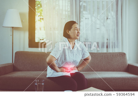 Elderly asian woman having stomachache while sitting on sofa at home,Senior female suffering from abdominal pain Elderly asian woman having stomachache while sitting on sofa at home,Senior female suffering from abdominal pain 59364594