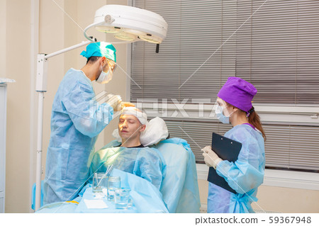 The surgeon gives injections to the head. Baldness treatment. Hair transplant. Surgeons in the 59367948