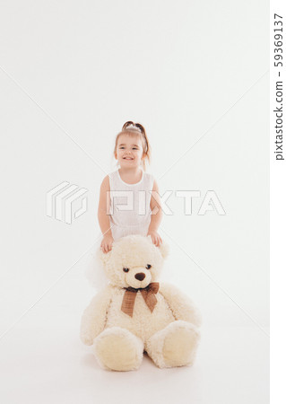 a small child with toy Taddy bear. Girl playing on white background. Concept of gift, childhood 59369137