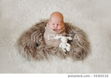 a small child in a basket sucks with toy white rabbit. concept of childhood, healthcare, IVF, gift 59369138