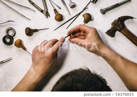 The jeweler polishes the gold ring at his workplace The jeweler polishes the gold ring at his workplace 59370055
