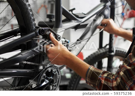 Male mechanic working in bicycle repair shop using tools 59375236
