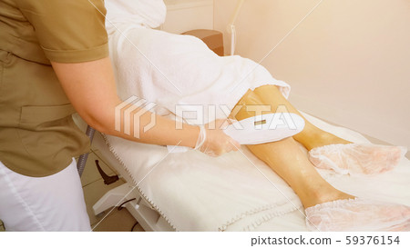 nurse hands slide laser head on gelled leg close view 59376154