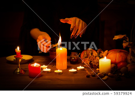 Witch burns a herb on the altar in the dark. Female hands with sharp black nails do magic among Witch burns a herb on the altar in the dark. Female hands with sharp black nails do magic among 59379924