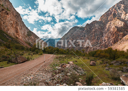 Panorama of road to the gorge of mountains on background of beautiful snowy mountain peaks in cloudy Panorama of road to the gorge of mountains on background of beautiful snowy mountain peaks in cloudy 59381585