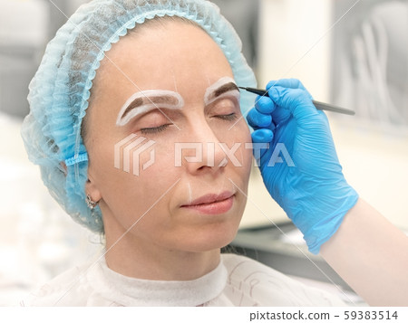 Coloring eyebrows with henna in the beauty salon. 59383514