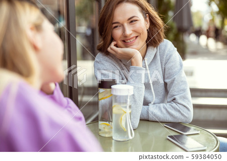 Pleased young woman talking with her friend 59384050