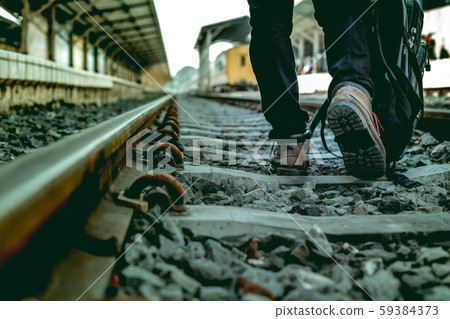 The single young man with bag walking on the railroad alone. 59384373