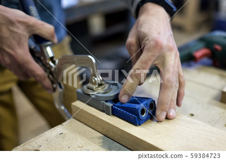 Carpenter installs the furniture hinge. Pocket hole joinery concept. 59384723