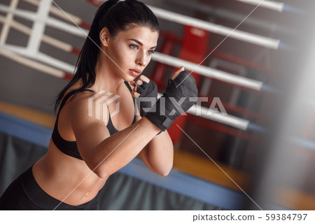 Boxing. Woman boxer with bandage around hands exercise hit near ring concentrated Boxing. Woman boxer with bandage around hands exercise hit near ring concentrated 59384797