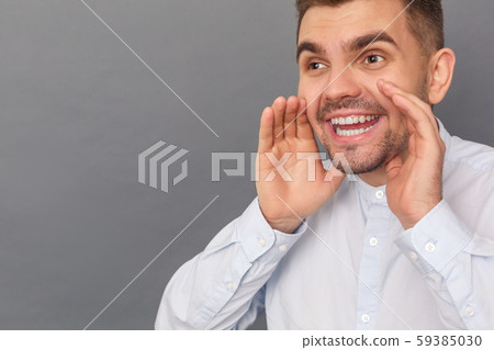 Freestyle. Young man studio standing isolated on grey smiling screaming close-up 59385030