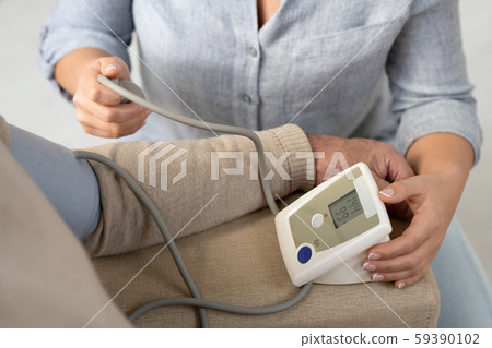 Hands of woman with tonometer helping senior father to measure blood pressure Hands of woman with tonometer helping senior father to measure blood pressure 59390102