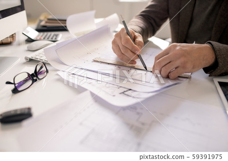 Hands of architect with pencil and ruler drawing line while working over sketch Hands of architect with pencil and ruler drawing line while working over sketch 59391975