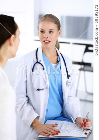 Doctor and patient during consultation. Physician at work filling up medication history record while 59395172