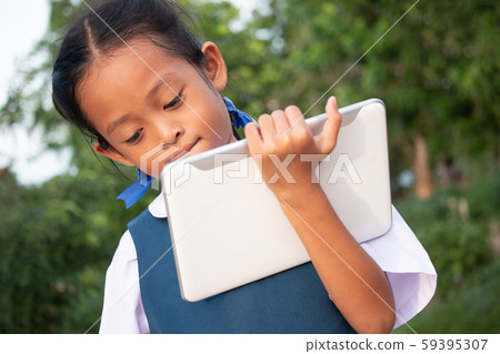 Happy little girl holding tablet PC outdoors in Happy little girl holding tablet PC outdoors in 59395307
