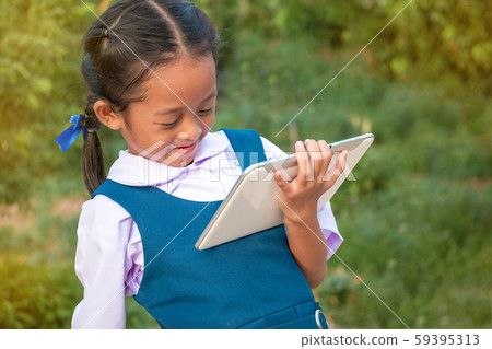 Happy little girl holding tablet PC outdoors in Happy little girl holding tablet PC outdoors in 59395313