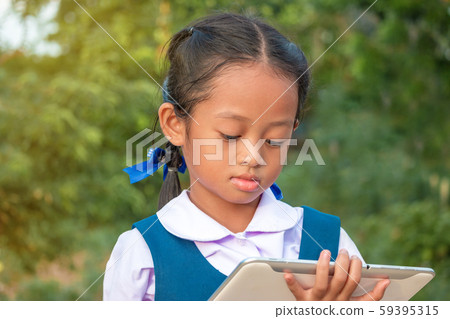 Happy little girl holding tablet PC outdoors in Happy little girl holding tablet PC outdoors in 59395315