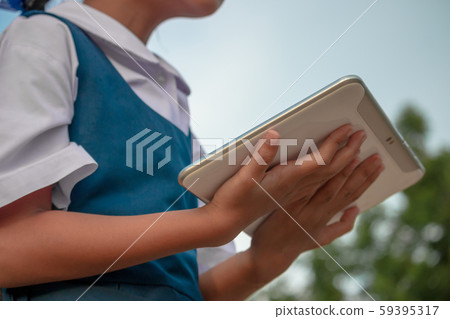Happy little girl holding tablet PC outdoors in Happy little girl holding tablet PC outdoors in 59395317