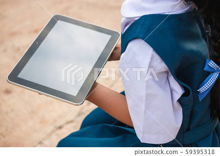 Happy little girl holding tablet PC outdoors in Happy little girl holding tablet PC outdoors in 59395318