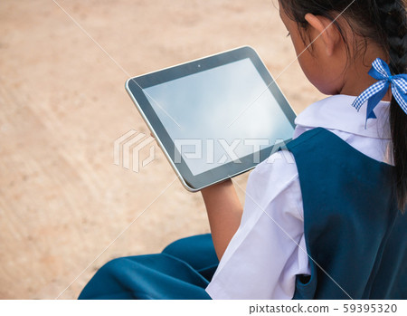 Happy little girl holding tablet PC outdoors in Happy little girl holding tablet PC outdoors in 59395320