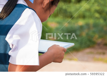 Happy little girl holding tablet PC outdoors in Happy little girl holding tablet PC outdoors in 59395322