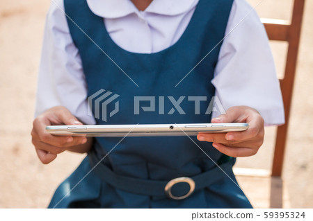Happy little girl holding tablet PC outdoors in Happy little girl holding tablet PC outdoors in 59395324