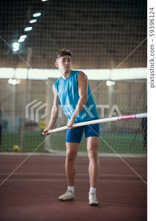 Pole vaulting - young guy in a blue suit is standing with a pole in hands Pole vaulting - young guy in a blue suit is standing with a pole in hands 59396124