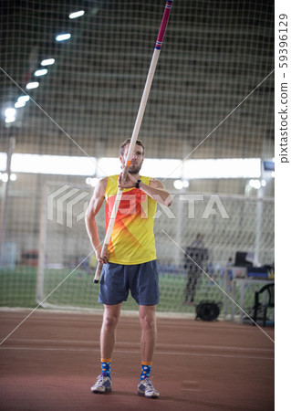 Pole vaulting - man in yellow shirt is standing with a pole in hands Pole vaulting - man in yellow shirt is standing with a pole in hands 59396129